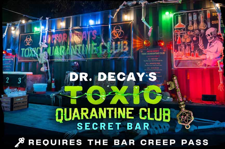 A toxic wasteland-themed outdoor bar made from shipping containers, decorated with hanging skeletons, neon green lights, and biohazard warning signs. The text reads "Dr. Decay's Toxic Quarantine Club."